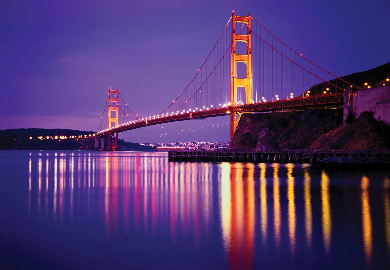 The Golden Gate Bridge at dusk with the lights of San Francisco behind it