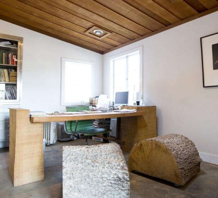 A slab desk on wood-block legs in Evan Shively's timber-ceilinged studio at Arborica