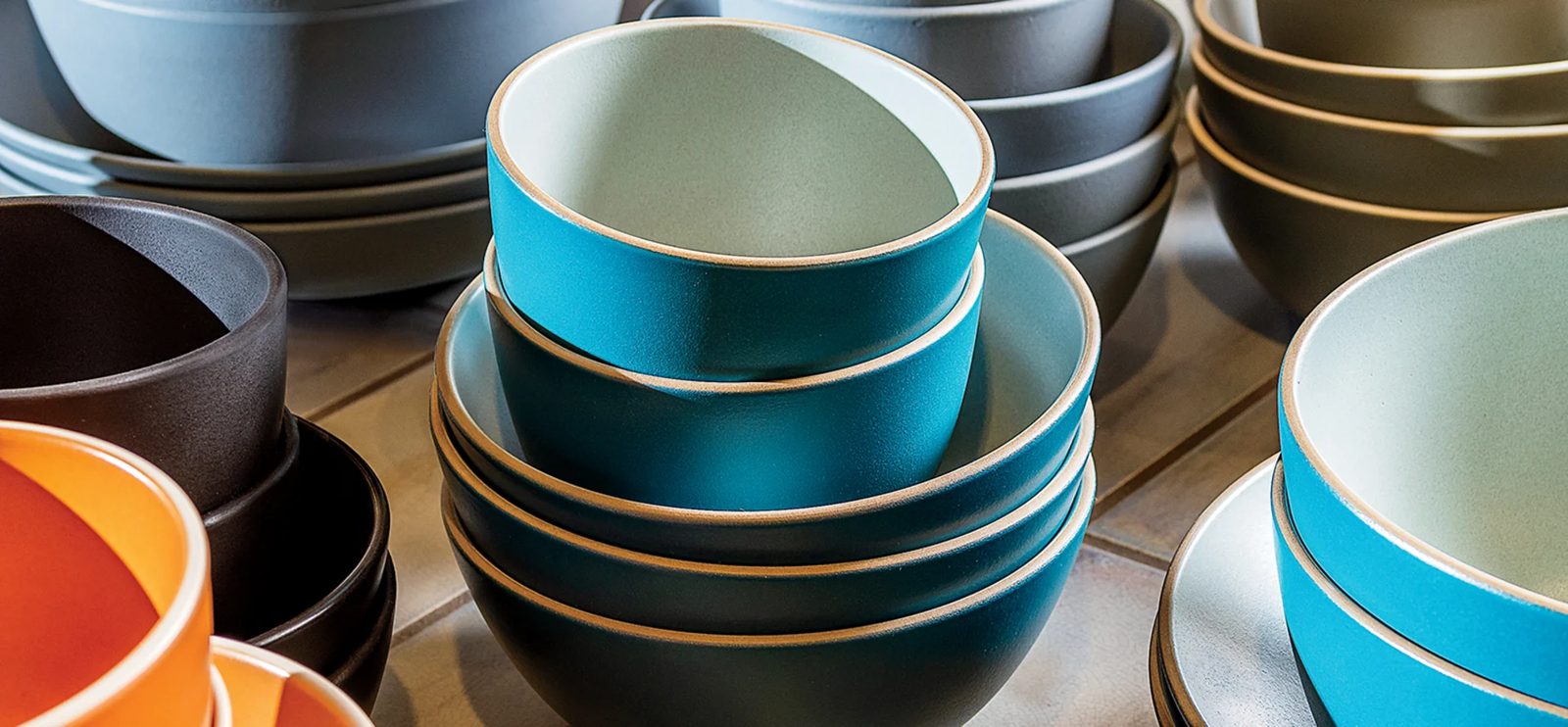 A stack of Heath Ceramics bowls in blue, black and orange
