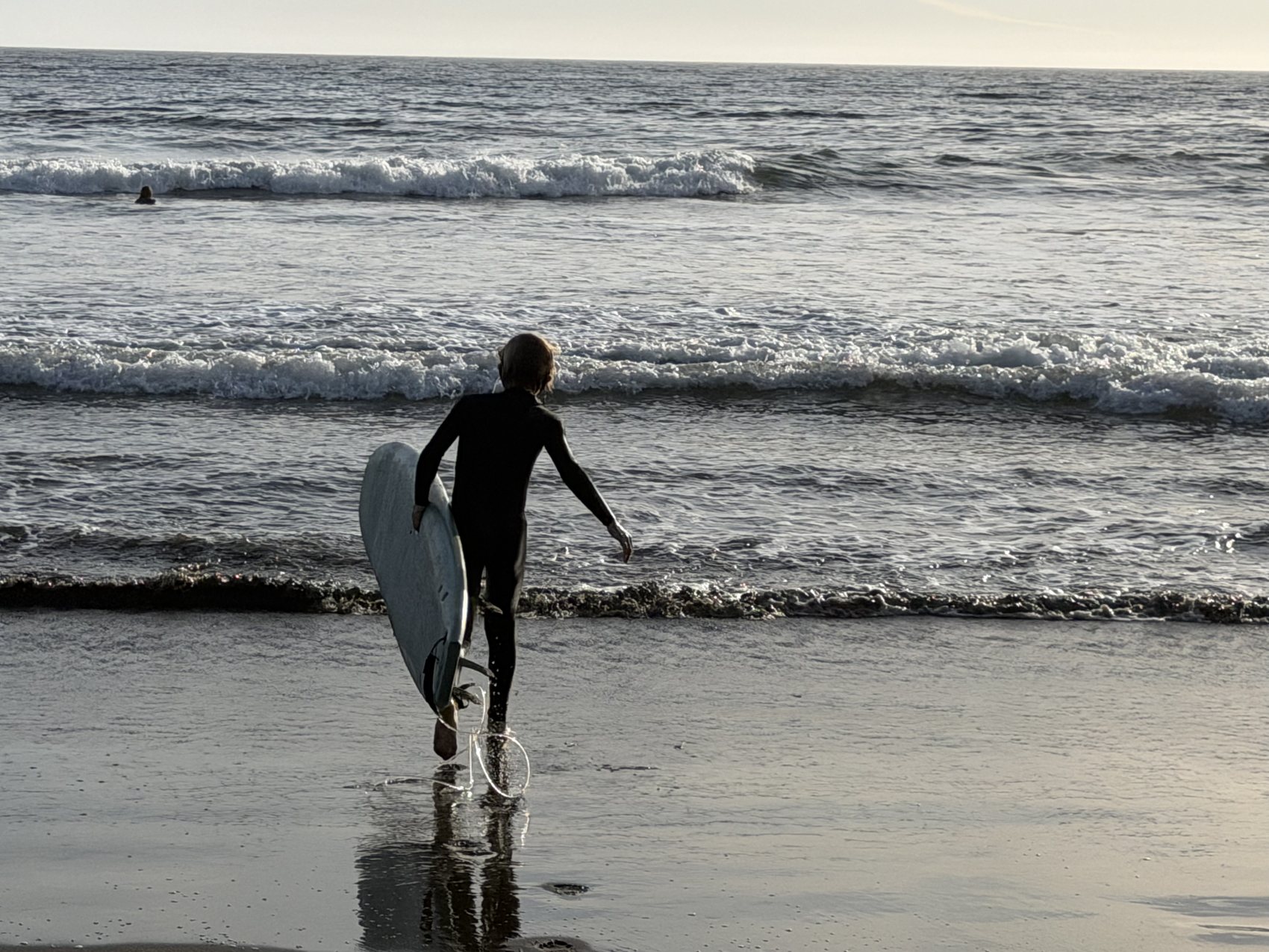 A surfer carrying a board into the water at Stinson Beach