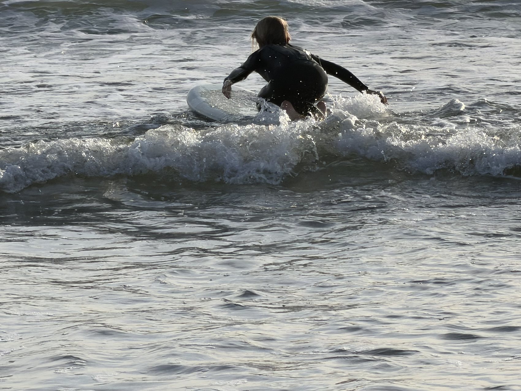 A young surfer riding a small wave at Stinson Beach