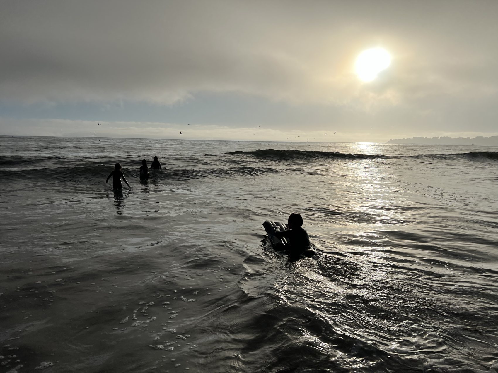 Surfers in the water at sunset, Stinson Beach